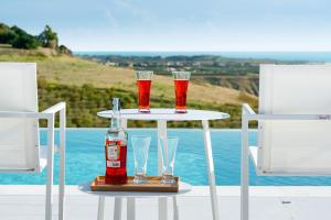 a table with two drinks and a bottle and two chairs at Camemi in Seccagrande