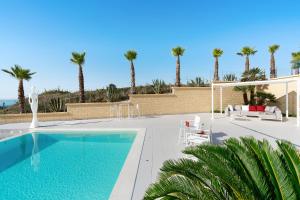 a swimming pool with palm trees in the background at Camemi in Seccagrande +48 photos