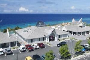 een groot gebouw met auto's geparkeerd op een parkeerplaats bij One Bedroom Apartment Near the Beach in Jan Thiel