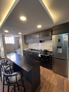 a kitchen with stainless steel appliances and black cabinets at Elegante departamento in Iquique