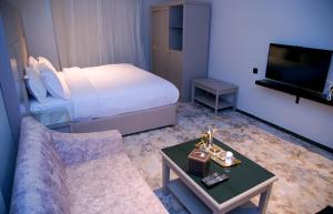 a hotel room with a bed and a couch and a tv at Sharz Hotel in Buraydah