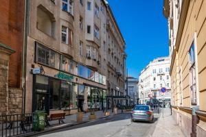 a car driving down a city street with buildings at Vintage Home next to Central Market Hall in Budapest