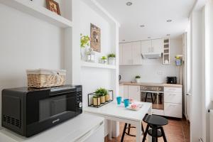 a white kitchen with a microwave and a table at Vintage Home next to Central Market Hall in Budapest