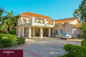 a house with a car parked in the driveway at LAIKIPIA WHITE HOUSE-NANYUKI in Timau