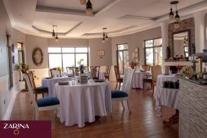 un restaurante con mesas y sillas con mantel blanco en LAIKIPIA WHITE HOUSE-NANYUKI, en Timau