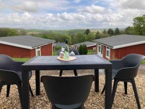 a black table with a bottle of wine and chairs at Caban Croeso-The Welcome Cabin, Holiday let, near Mansion House Llansteffan in Llanstephan