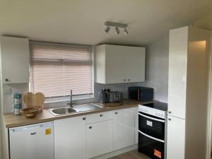 a kitchen with white cabinets and a sink at Caban Croeso-The Welcome Cabin, Holiday let, near Mansion House Llansteffan in Llanstephan