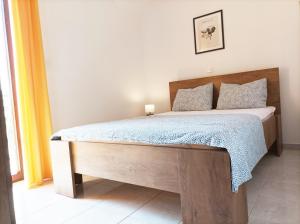 een slaapkamer met een groot bed met een houten frame bij Slavica Olive 3 in Brodarica