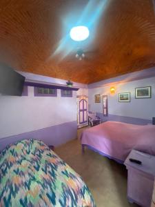 1 dormitorio con cama rosa y techo de madera en Casa Morada en Bernal