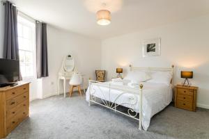 a white bedroom with a bed and a television at Algernon House in Alnwick