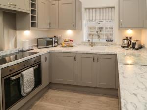 a kitchen with white cabinets and a sink at 9 Station Cottages in Belford