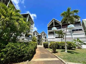 una pasarela frente a un edificio con palmeras en Studio cosy plage et piscine à Bas Du Fort, en Le Gosier