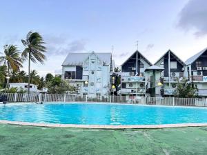 a large blue swimming pool in front of some buildings at Studio cosy plage et piscine à Bas Du Fort in Le Gosier