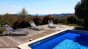 einen Pool mit Stühlen und eine Holzterrasse in der Unterkunft Le Clos des Mimosas in Saint-Andéol-de-Vals