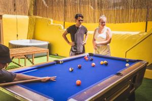 two people standing next to a pool table at The Macarena Beach Hostel in Lagos