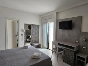 1 dormitorio con 1 cama y TV en la pared en Hotel Admiral en Bellaria-Igea Marina