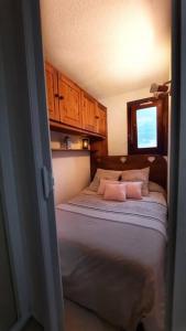 a small bedroom with a bed with pink pillows at Super appartement Cocooning vu Mont Blanc in Sallanches