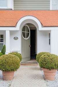 a white house with a green door and bushes at Marie Siska Boutique hotel in Knokke-Heist