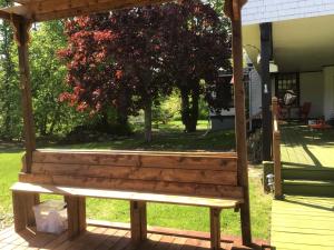 un banco de madera sentado en la parte superior de un porche en Celtic Mansion Annfield Manor en Little Bras dʼOr