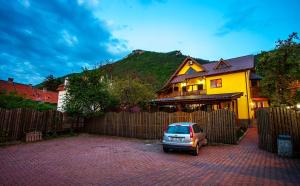 a car parked in front of a yellow house at Pension Brasovu Vechi in Braşov