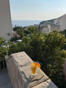 um copo de sumo de laranja sentado numa borda de pedra em MONTEFIN HOUSE em Petrovac na Moru
