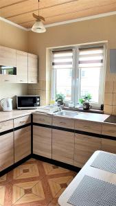 een keuken met houten kasten, een wastafel en een raam bij Domki u Marka in Polańczyk