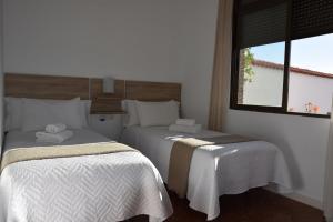 um quarto com 2 camas com lençóis brancos e uma janela em SIERRA LAGO em Córdoba