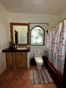 y baño con aseo, lavabo y espejo. en Casa Familia, en Cabo Matapalo