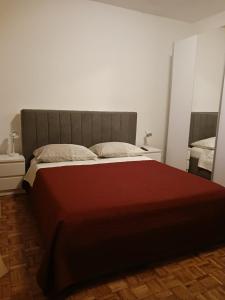 a bedroom with a large bed with a red blanket at Apartmani Valerija i Joso in Bibinje