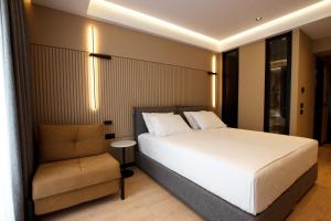 1 dormitorio con 1 cama blanca y 1 silla en Caramel Boutique Hotel en Gjirokastër