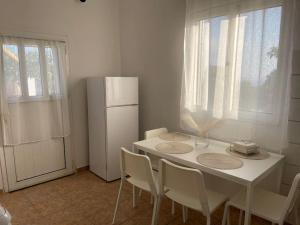 a kitchen with a white table with chairs and a refrigerator at Cantera house, Kalokairines KIT in Kýthira