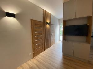 a living room with a television and a wooden floor at Apartamenty A1 in Gdynia