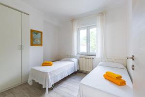 2 letti in una camera bianca con finestra di Le Castagne Apartments Ischia a Ischia