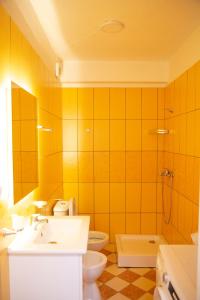 a yellow bathroom with a sink and a toilet at Lulu Suites - Moka in Golem