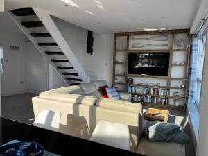 a living room with a couch and a tv at Beachfront retreat apartment with amazing terrace in Hastings