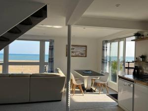a living room with a couch and a table with chairs at Beachfront retreat apartment with amazing terrace in Hastings