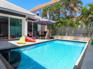 una piscina con sombrilla junto a una casa en CityHouse-OSCAR,pool villa 4Bedrooms-Jacuzzi-walking Street 10min en Pattaya South