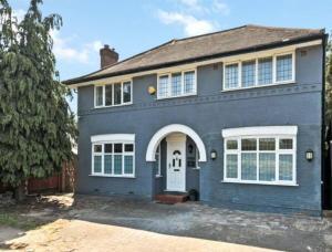 una casa azul con una puerta blanca en Large family home near Richmond Park, en New Malden