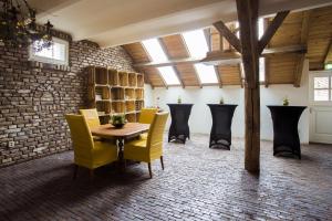 a room with yellow chairs and a table and a brick wall at Vakantie Meerlo in Meerlo