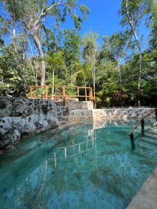 a large pool of water with a wooden bridge at Selvaluna cabaña eco-chic in Tulum
