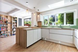 une cuisine avec des placards blancs et une grande fenêtre dans l'établissement Large family home near Richmond Park, à New Malden