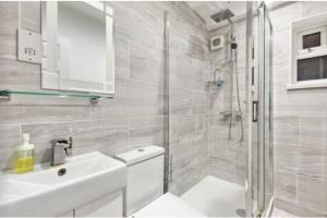 La salle de bains blanche est pourvue d'un lavabo et d'une douche. dans l'établissement Large family home near Richmond Park, à New Malden