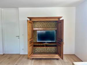 TV en un centro de entretenimiento de madera en una habitación en Seeparkvilla – Wohlfühlen am See und im Grünen, en Bregenz