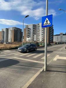 a car driving down a city street with a blue sign at Apartament spațios zona buna in Cluj-Napoca