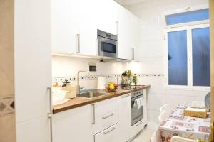 cocina blanca con fregadero y microondas en Apartamento en zona residencial cerca del Guggenheim, en Bilbao