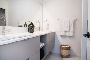 Baño blanco con lavabo y espejo en Ghost Peak by Revelstoke Vacations en Revelstoke