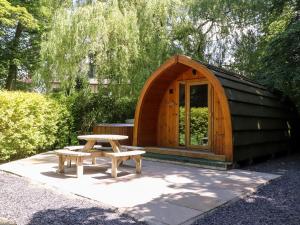 a wooden hut with a picnic table and a bench at Homewood Pod in Preston
