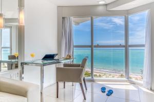 Hotel Brisa Praia Pajuçara في ماسيو: غرفة معيشة مع مكتب وإطلالة على المحيط
