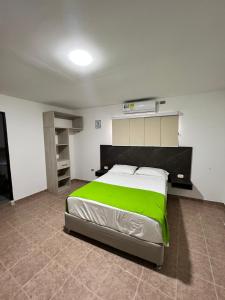 1 dormitorio con 1 cama grande con manta verde en Hotel Villa Maria Uribia, en Uribia