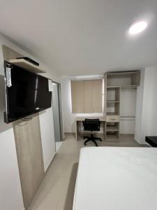 a room with a bed and a desk and a television at Hotel y Piscina Villa Maria Uribia in Uribia
